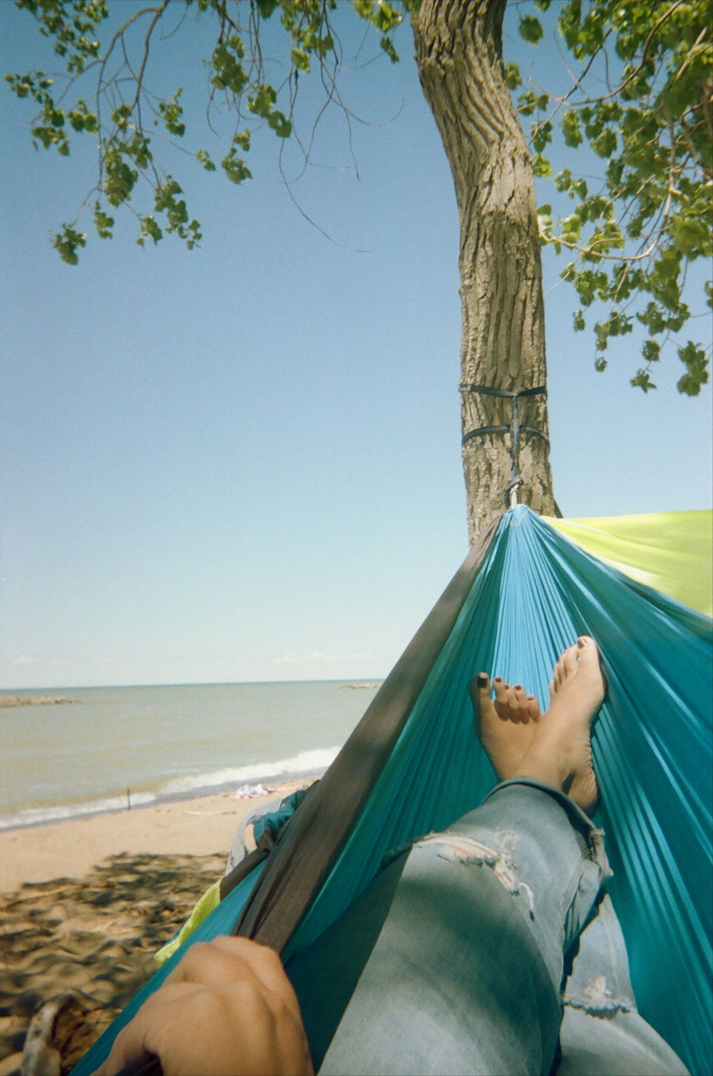 a person laying in a hammock on the beach