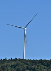 A wind turbine standing tall against a clear blue sky in a green landscape.