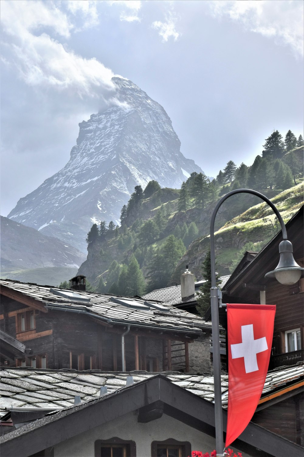 a swiss flag flying in front of a mountain