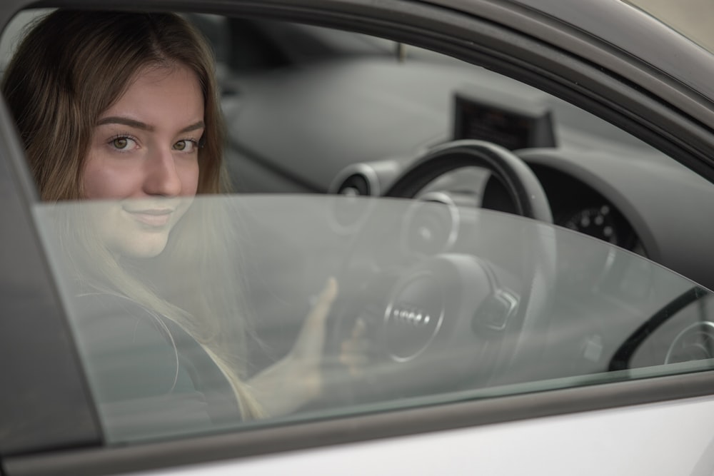 a woman sitting in a car holding a steering wheel