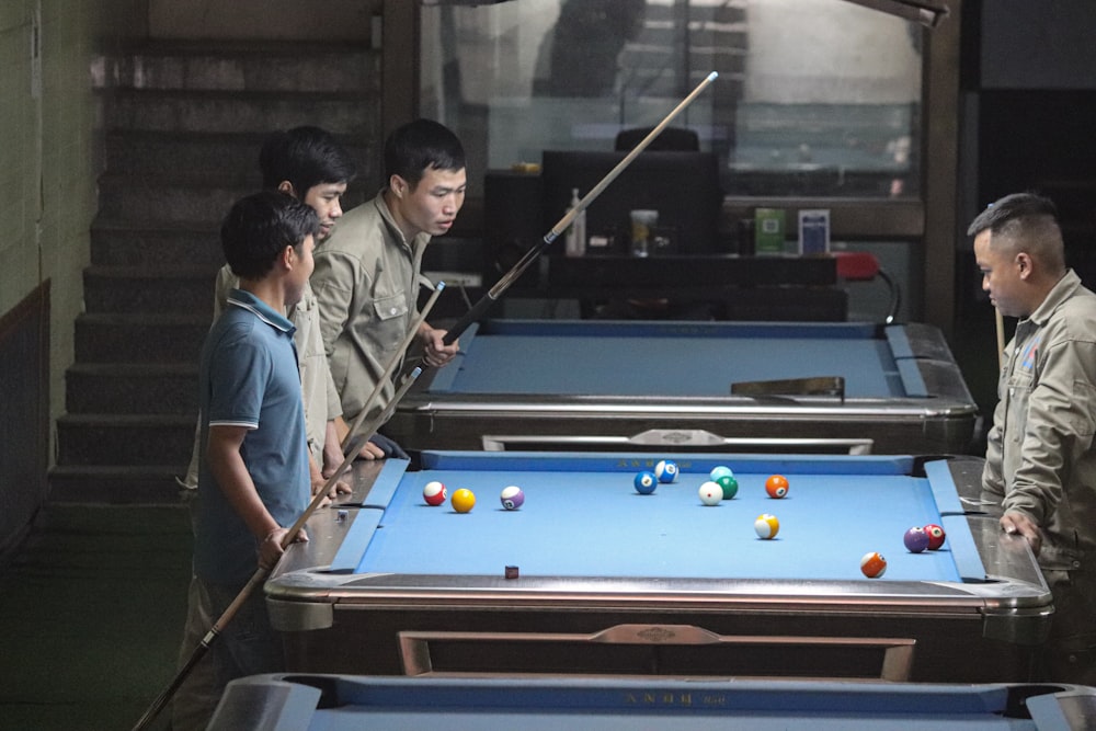 Un groupe d’hommes debout autour d’une table de billard