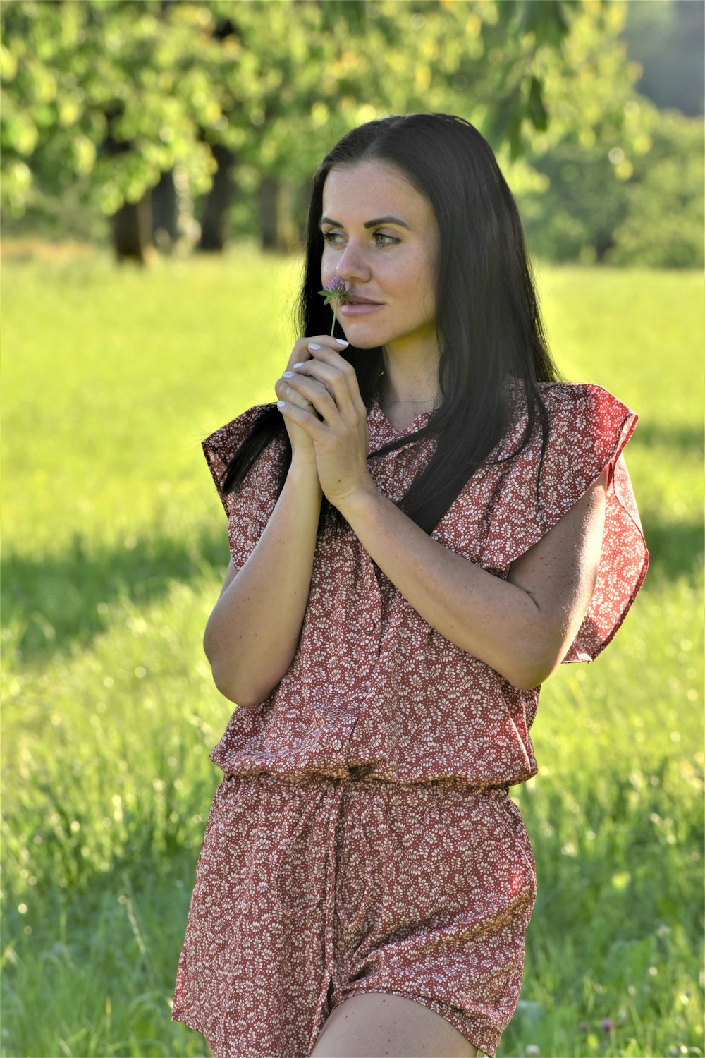 uma mulher em pé em um campo segurando uma flor