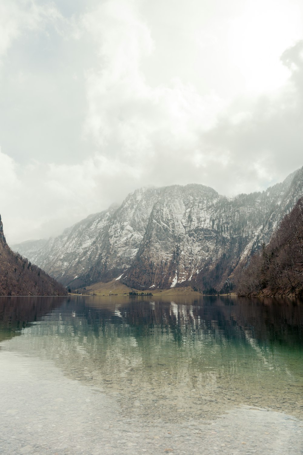 a body of water surrounded by mountains under a cloudy sky