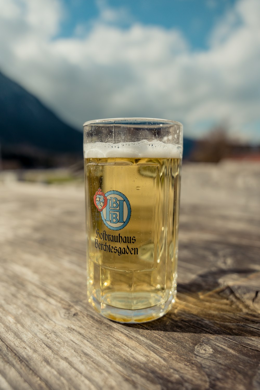 a glass of beer sitting on top of a wooden table