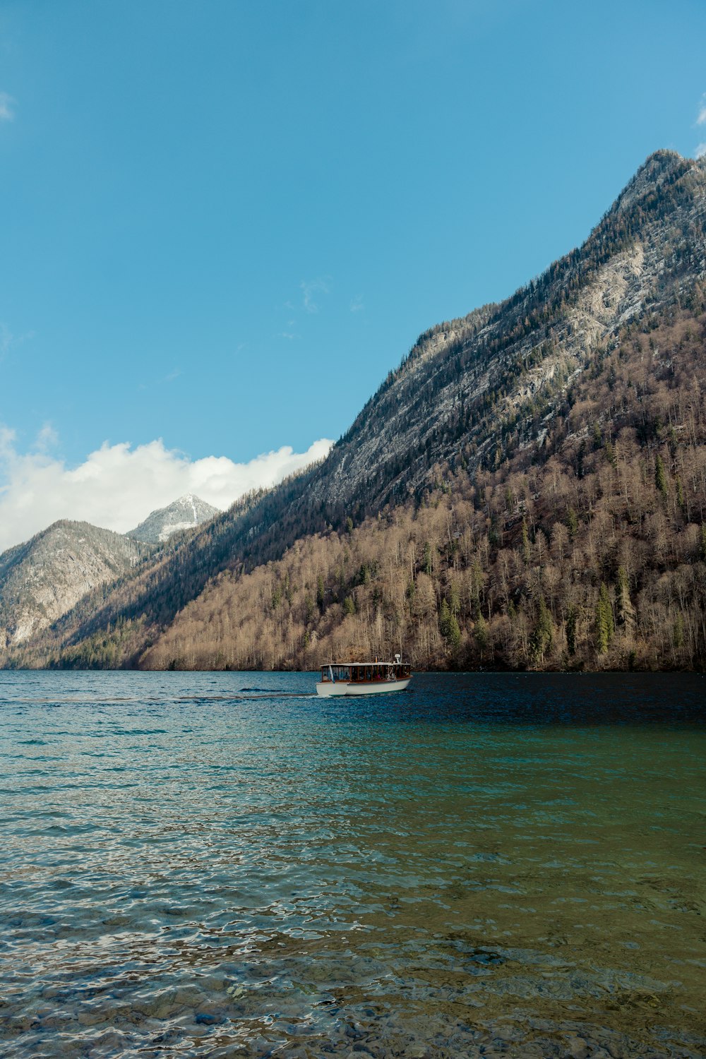a boat floating on top of a lake next to a mountain