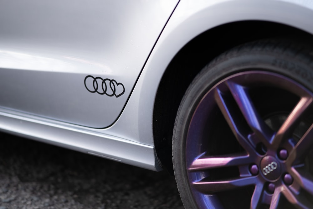 a close up of a silver car with purple rims