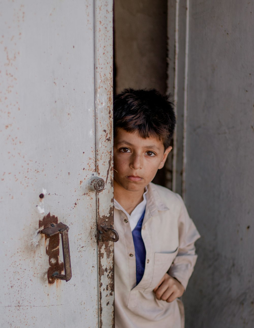 a young boy wearing a tie standing in a doorway