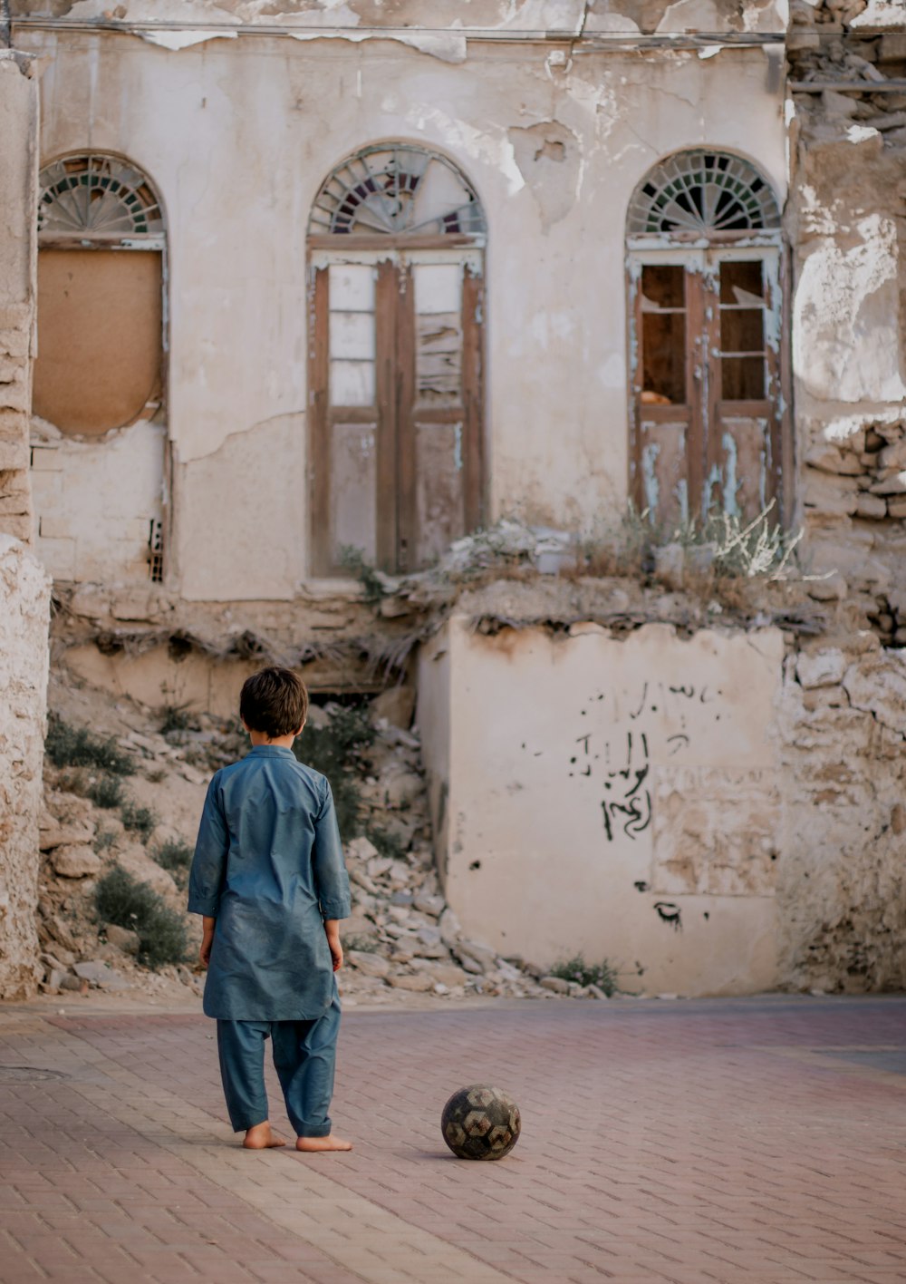 a young boy playing with a soccer ball in front of an old building