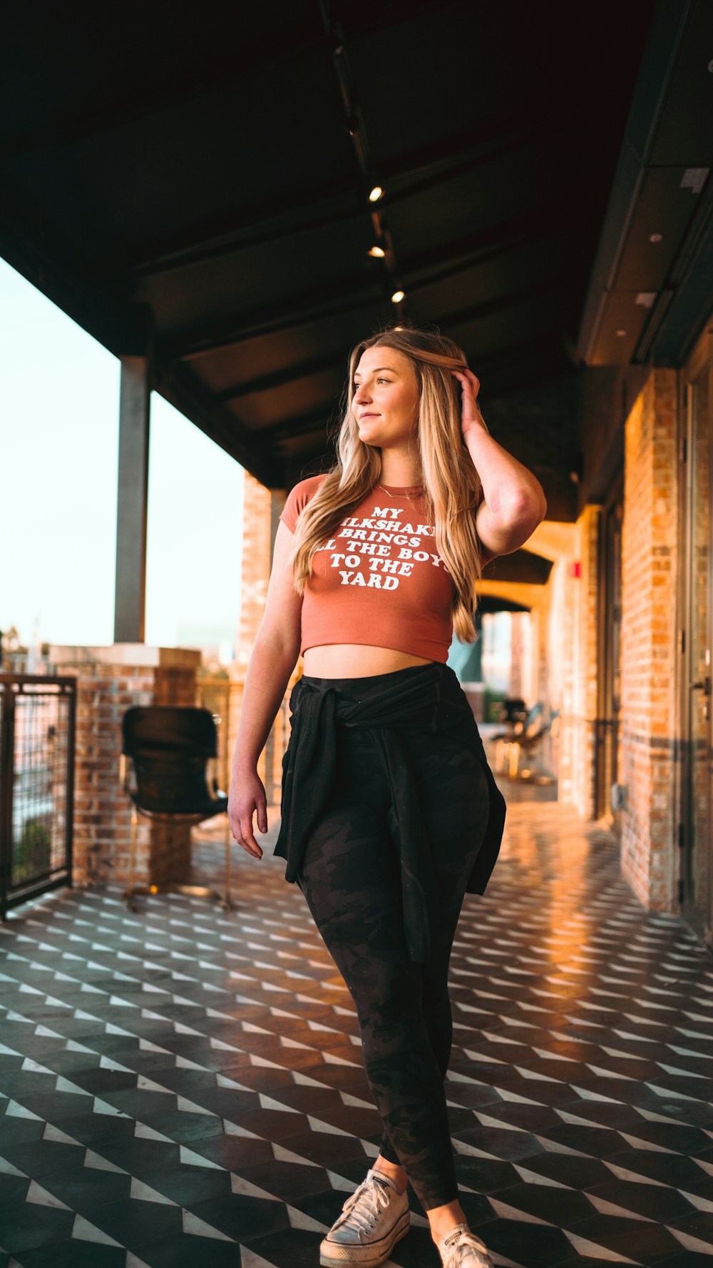 a woman standing on a tiled floor wearing a crop top