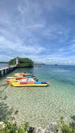 A group of friends laughing as they ride a bright yellow banana boat over sparkling blue waves.