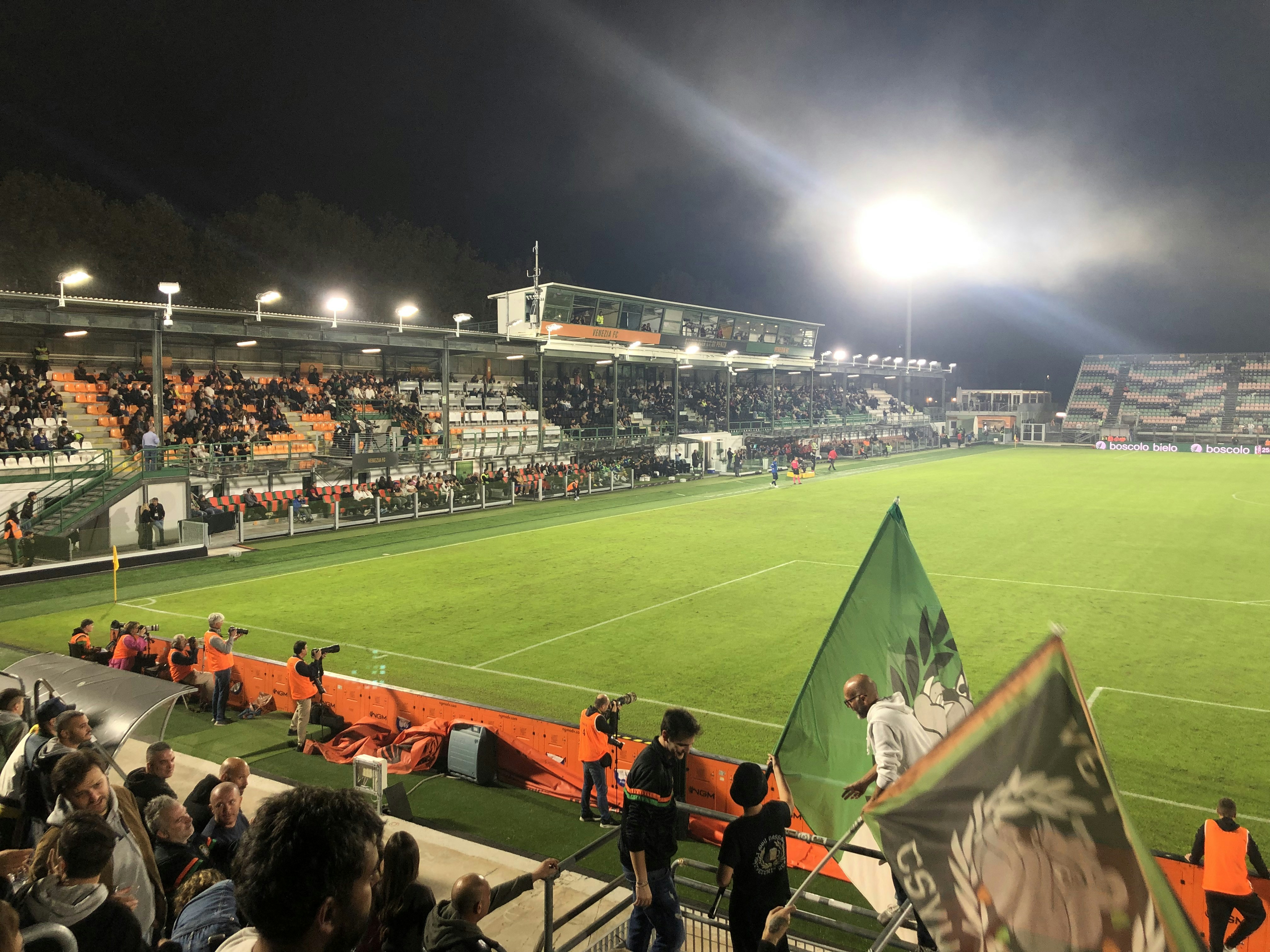 Football stadium with green pitch and bright floodlights, competitive sports gaming atmosphere