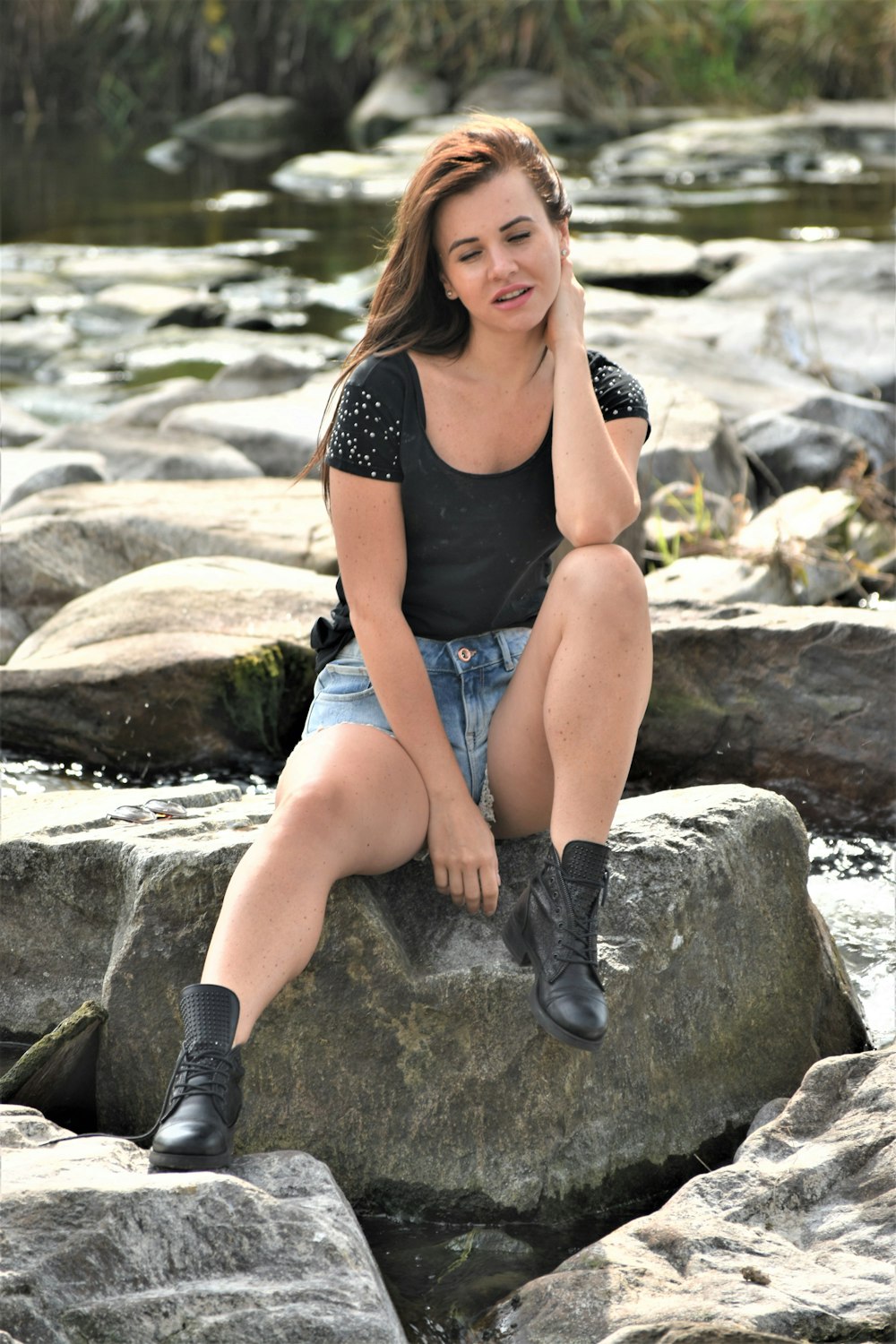 a woman sitting on top of a rock next to a river