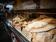 A modern food market stall displaying artisanal breads and cheeses under soft, natural lighting.