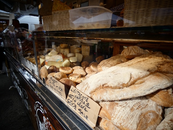 Close-up of local cheeses and artisanal breads displayed on rustic wooden tables at the market.