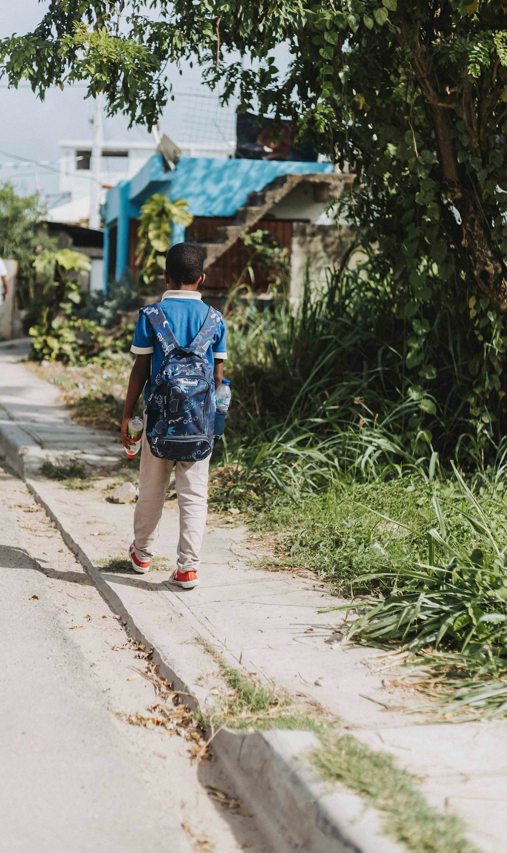 a young boy walking down a street with a backpack on