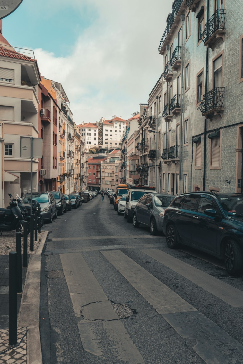 a street lined with parked cars next to tall buildings