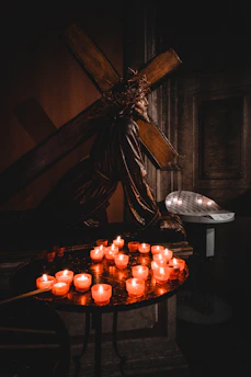 A serene close-up of the Sacred Heart of Jesus statue glowing softly in candlelight.