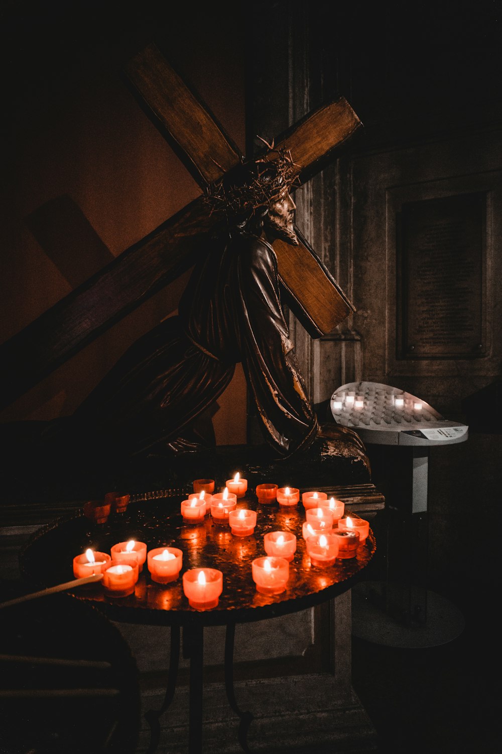a bunch of candles sitting on a table in front of a cross