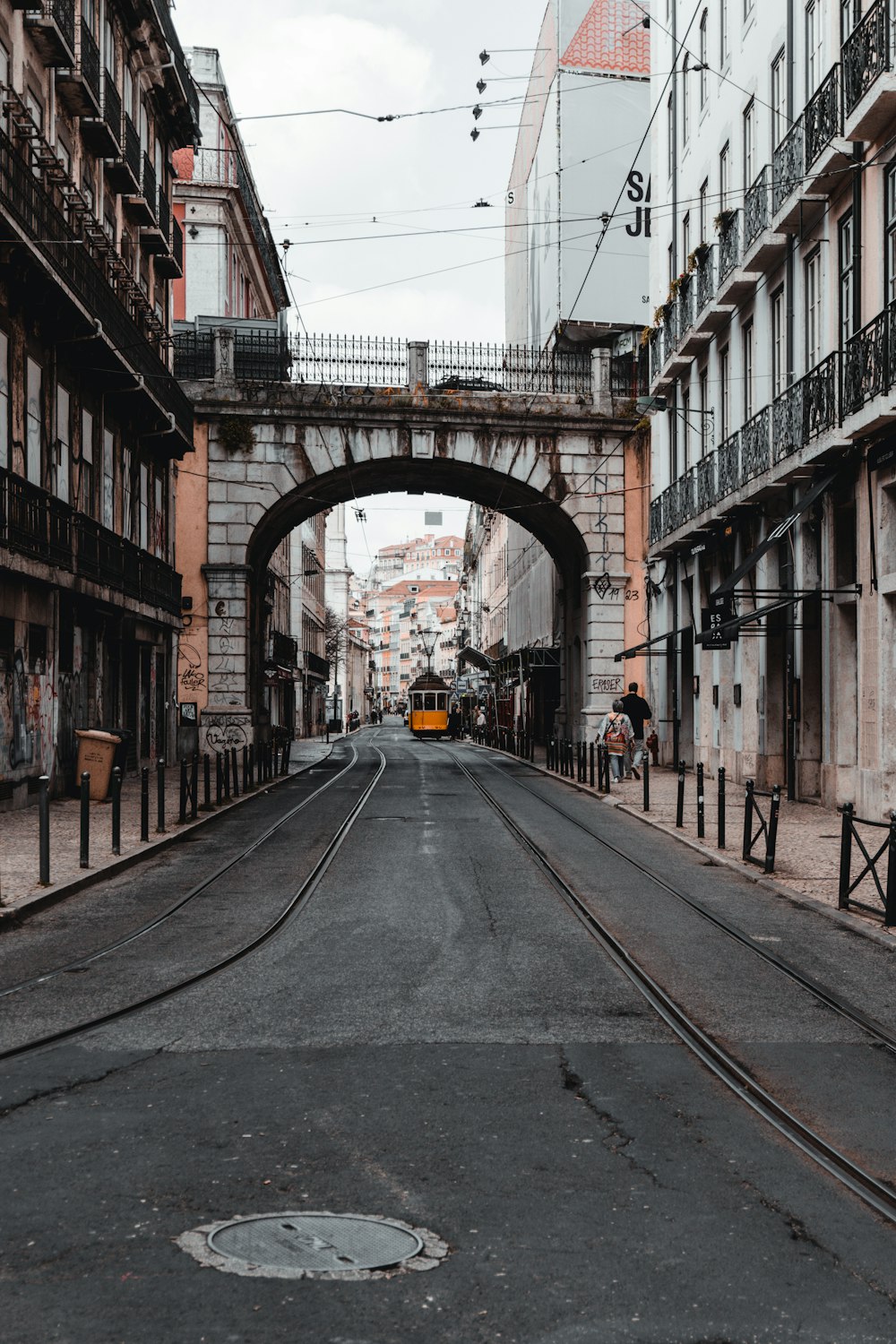a street with a train going under a bridge