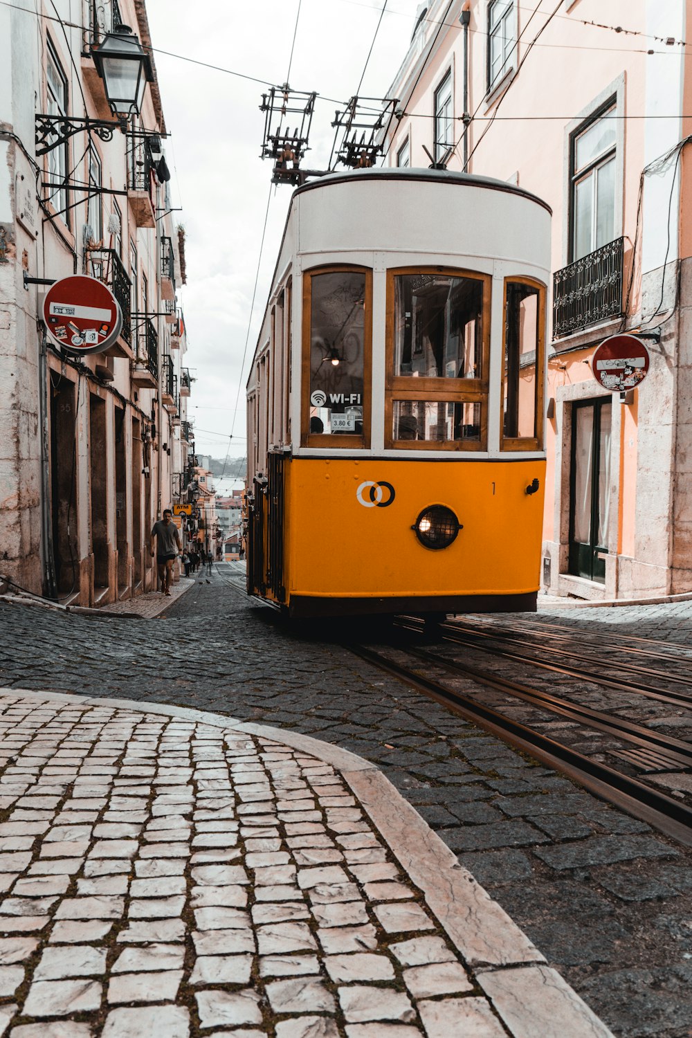 an orange and white trolley is going down a cobblestone street