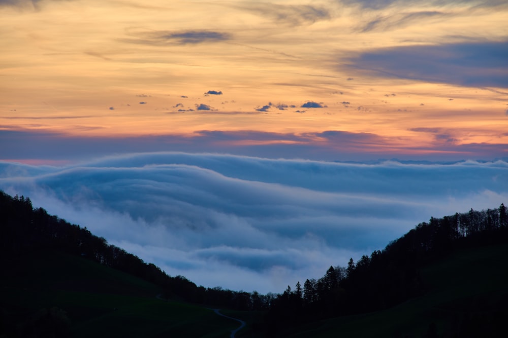 a mountain covered in clouds at sunset