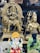 The image features an assortment of religious statues, including a golden deity riding a lion, a figure with a trident, a colorful elephant-headed figure, and a serene figure in a meditative pose. The vibrant and intricate designs display a range of expressions and symbolism.