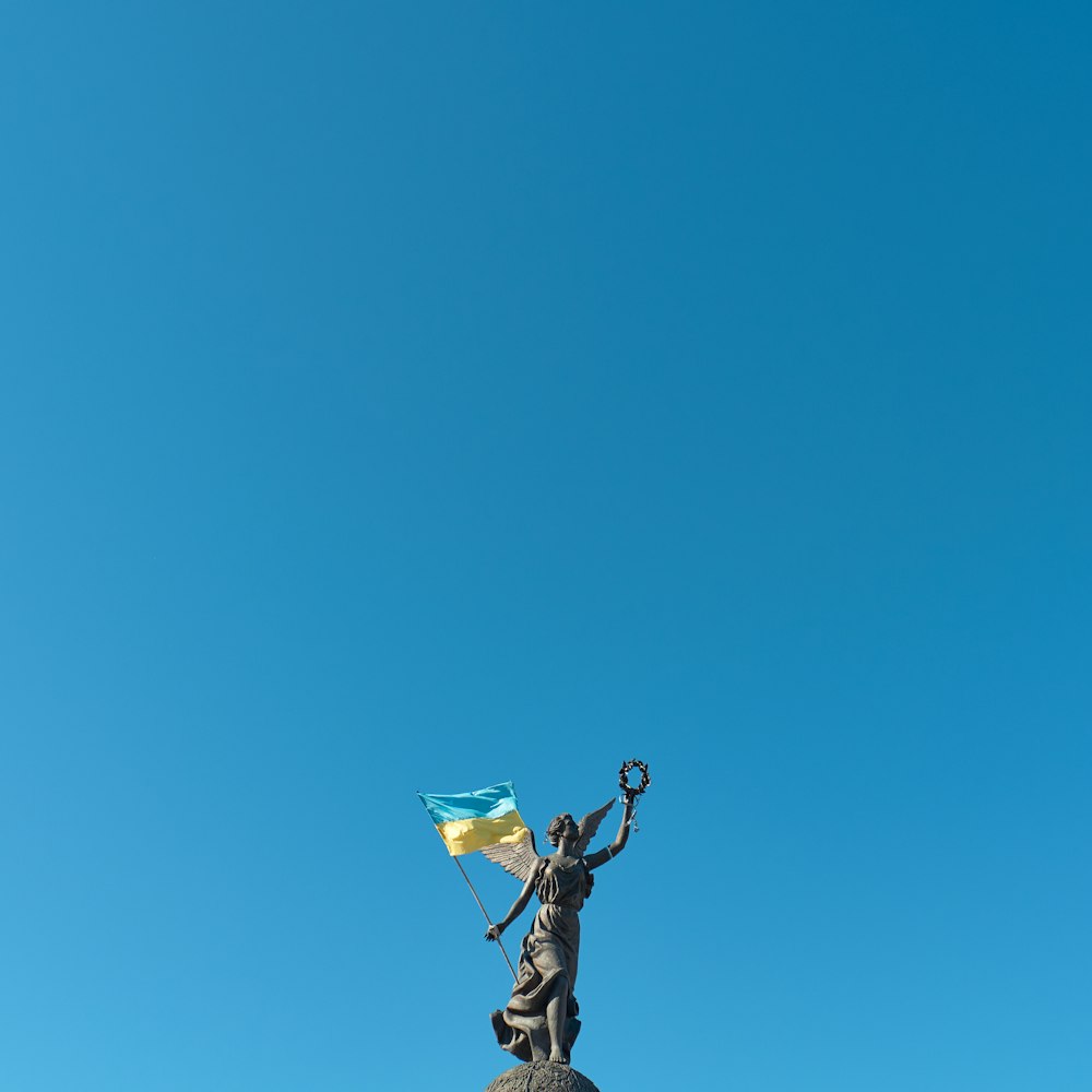 Eine Statue einer Frau, die eine Flagge auf einem Gebäude hält