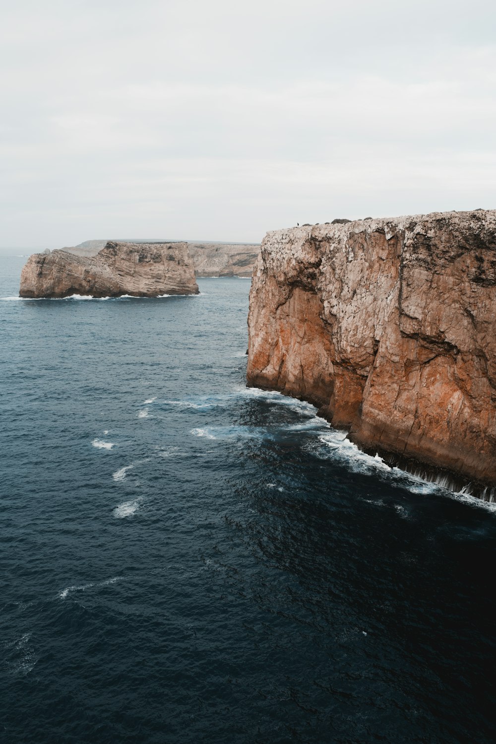 a large body of water next to a rocky cliff