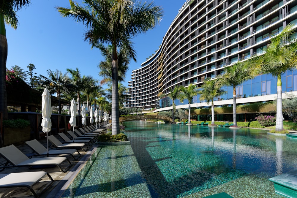 a hotel with a pool and lounge chairs next to it