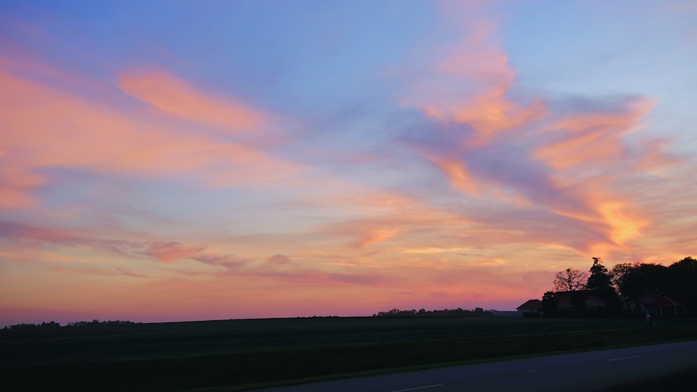 Un beau coucher de soleil sur une route rurale avec des nuages dans le ciel
