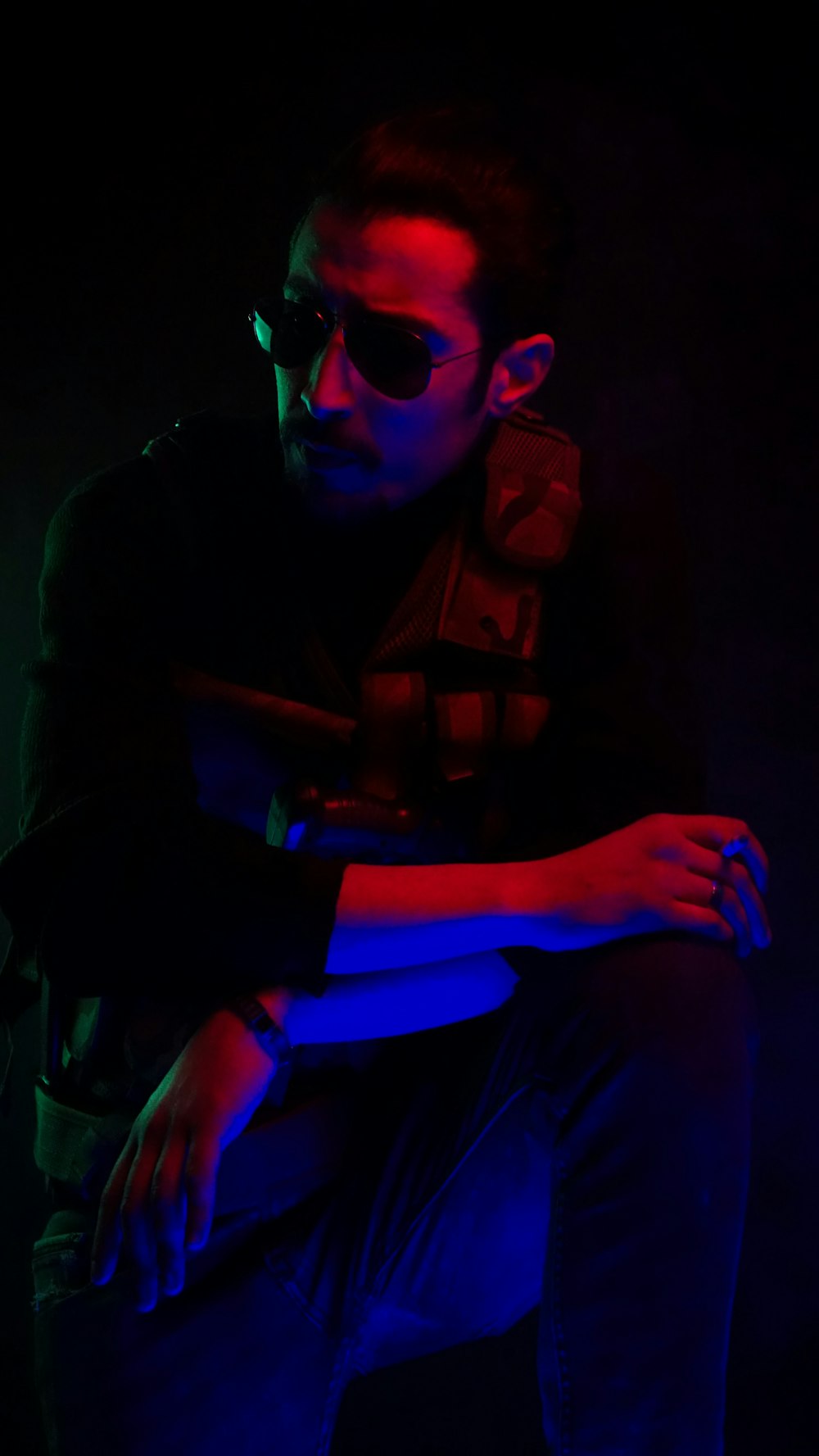 Un hombre sentado en la oscuridad con los brazos cruzados