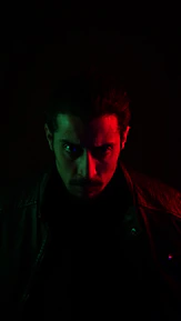 An intense close-up of a footballer’s focused eyes illuminated by neon lights.