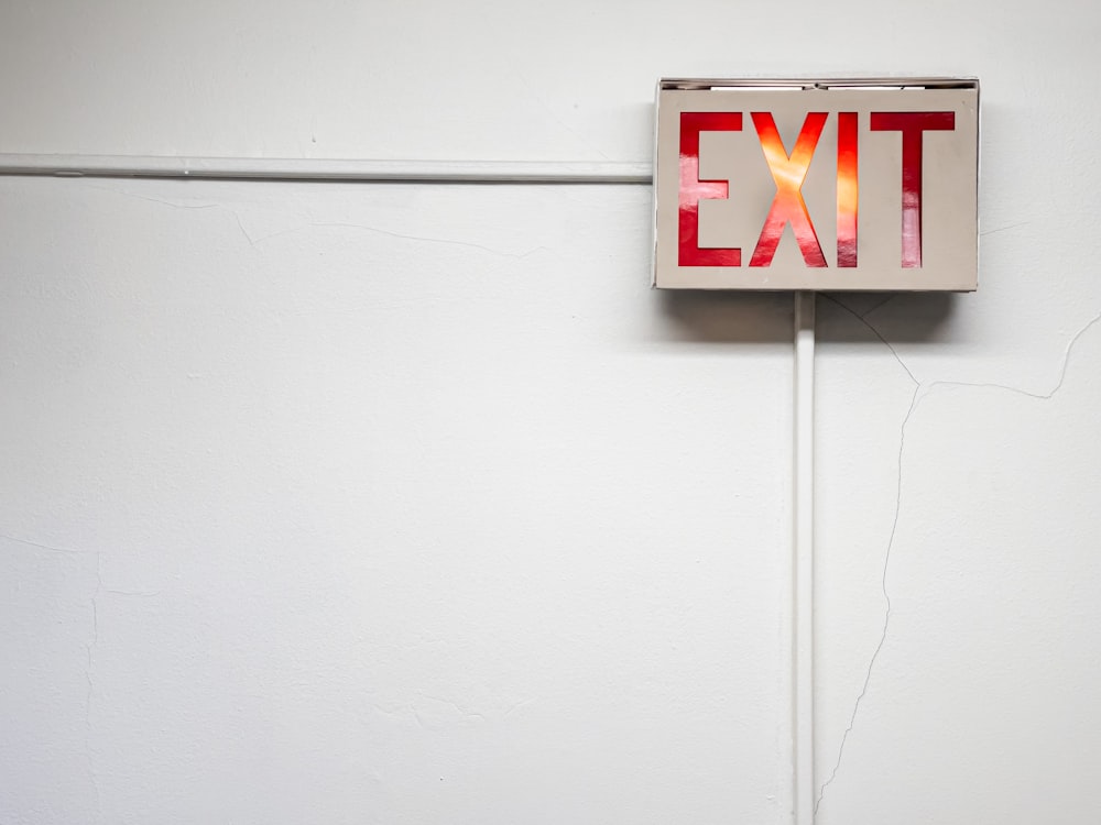 a red exit sign mounted on a white wall