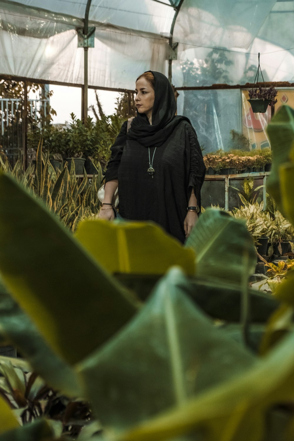 a woman standing in a greenhouse surrounded by plants