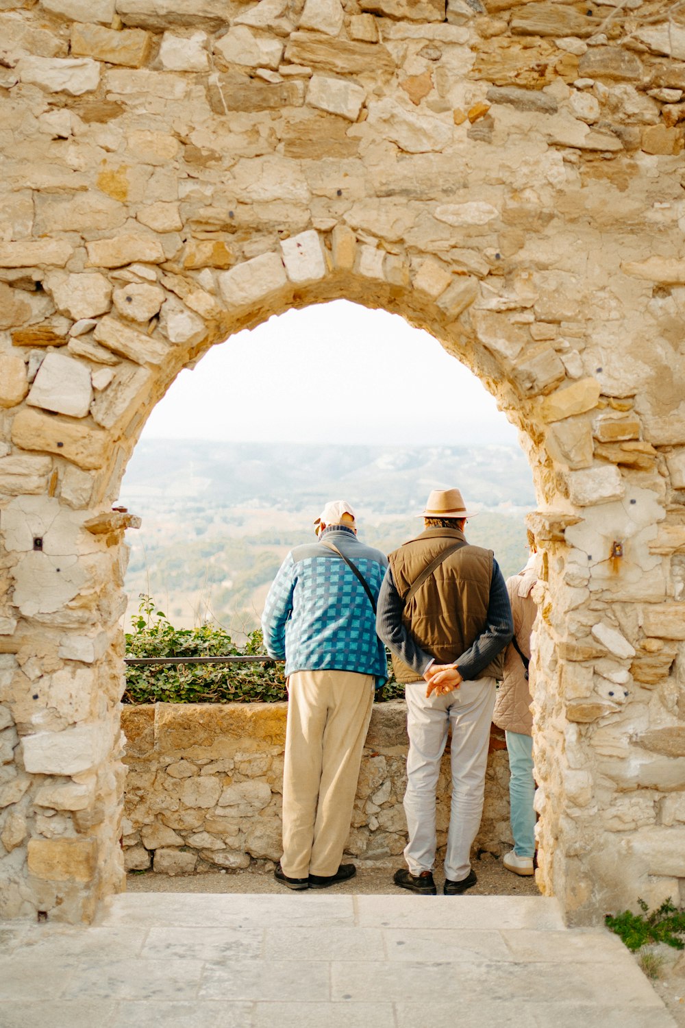 a couple of men standing next to each other on a stone wall