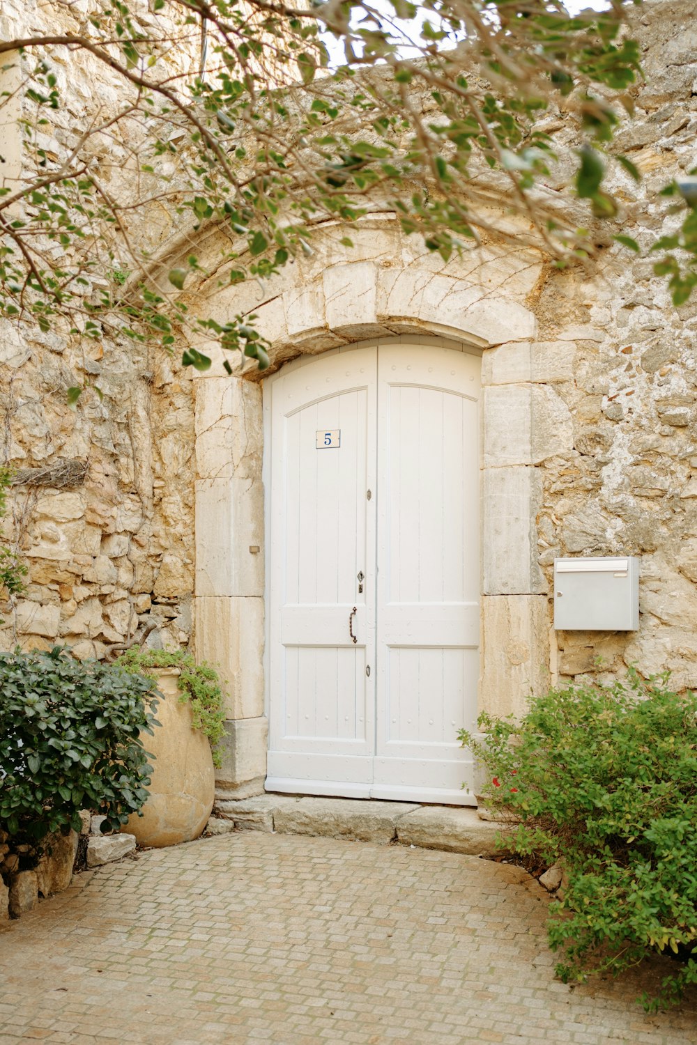 a stone building with a white door and a brick walkway