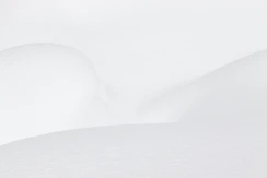Smooth white snow drifts with soft shadows and gentle curves