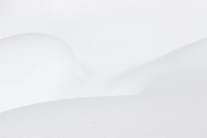 Smooth white snow drifts with soft shadows and gentle curves