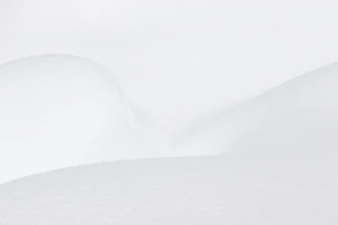 Smooth white snow drifts with soft shadows and gentle curves