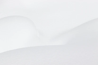 Smooth white snow drifts with soft shadows and gentle curves