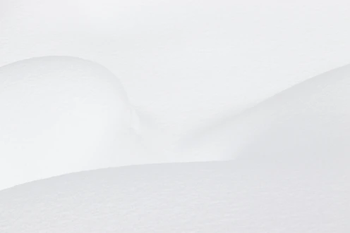 Smooth white snow drifts with soft shadows and gentle curves