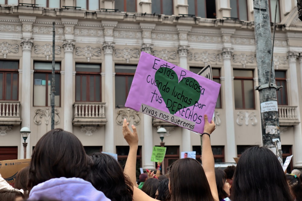 a group of people holding up signs in front of a building