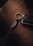 A keychain with a metallic spiral charm rests on a wooden surface alongside a car key. The keychain ring features engraved text, creating a luxurious and sophisticated impression.