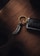 A keychain with a metallic spiral charm rests on a wooden surface alongside a car key. The keychain ring features engraved text, creating a luxurious and sophisticated impression.