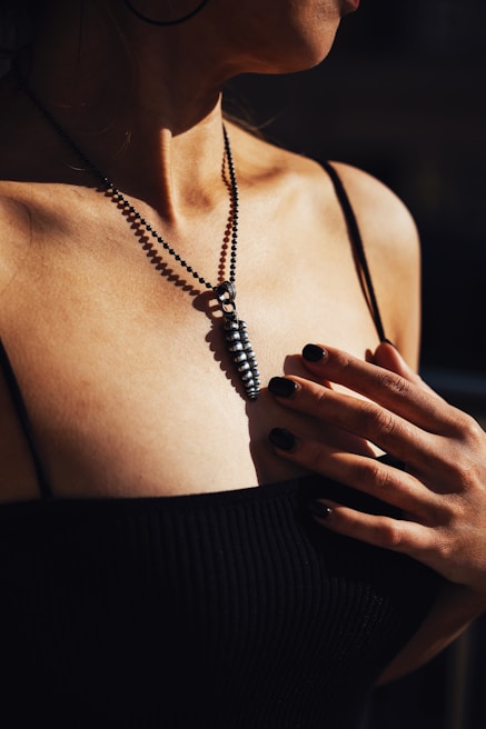 Close-up of a statement black top with elegant gold accents worn by an urban woman in natural light.