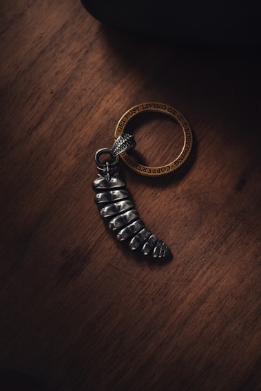A sleek custom metal keychain with a gear motif resting on a textured black surface.