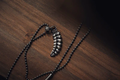 Close-up of a sleek silver necklace with sharp geometric pendants resting on a dark matte surface.