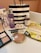 An arrangement of various cosmetic and skincare products displayed, including Clinique makeup remover, an eyeshadow palette, Kiehl's cleanser, vitamin eye mask, a pair of earrings, and several other makeup items. A black and white striped Sephora shopping bag is also present.
