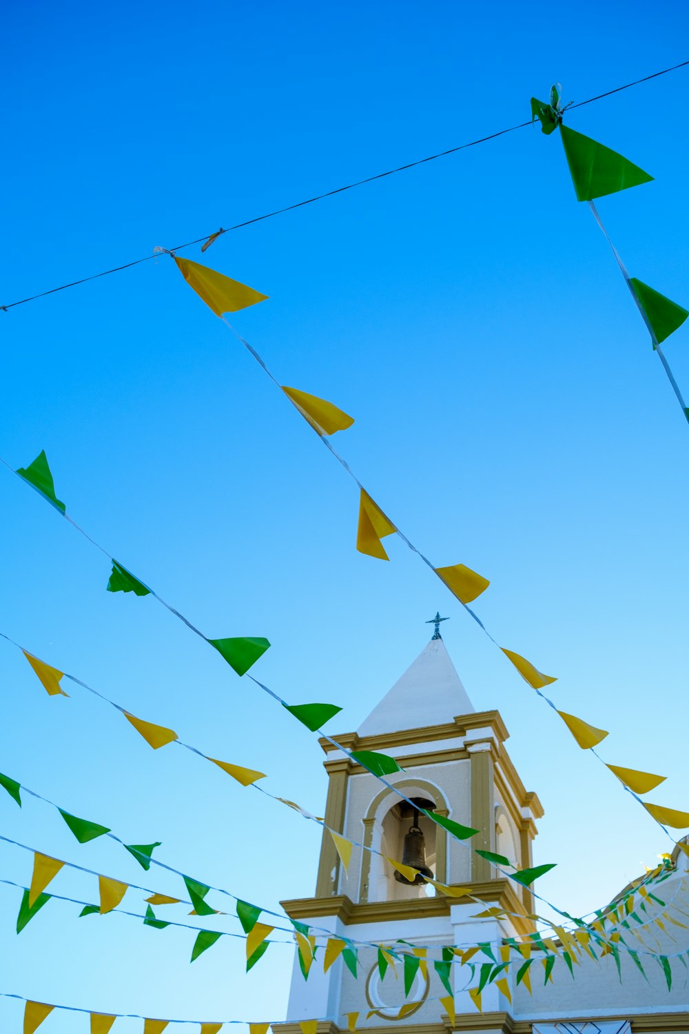 a church steeple with a bell tower and green and yellow flags
