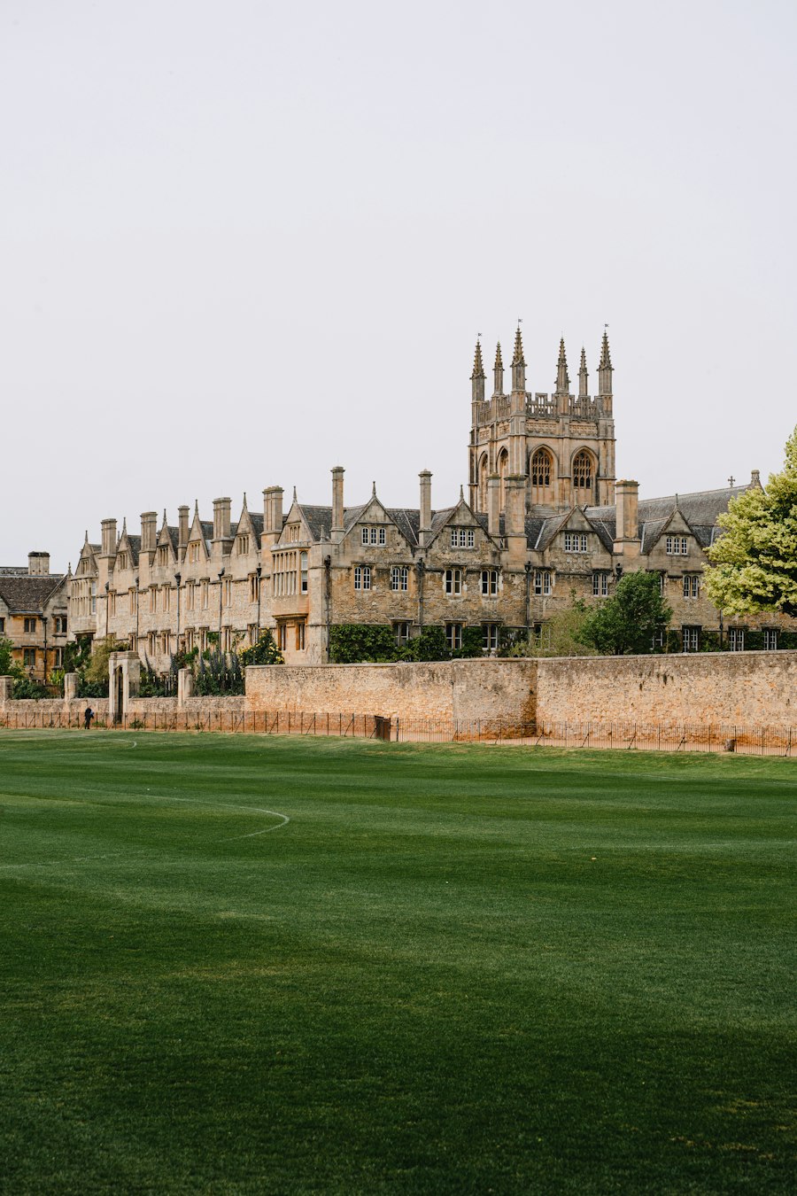 Historic Oxford college buildings beyond a green lawn